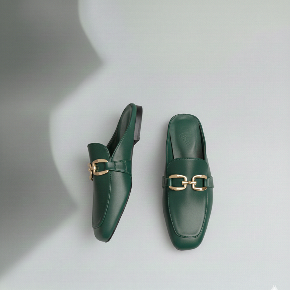 Pair of green loafers with gold buckles on a light gray background
