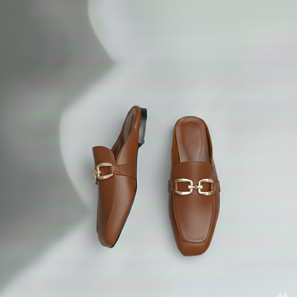 Pair of brown loafers with gold buckles on a light gray background