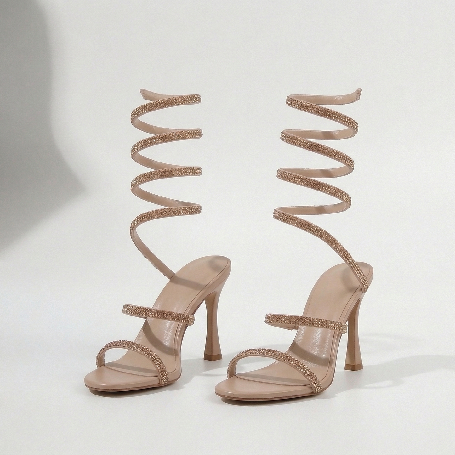 Pair of high-heeled sandals with spiral straps on a white background