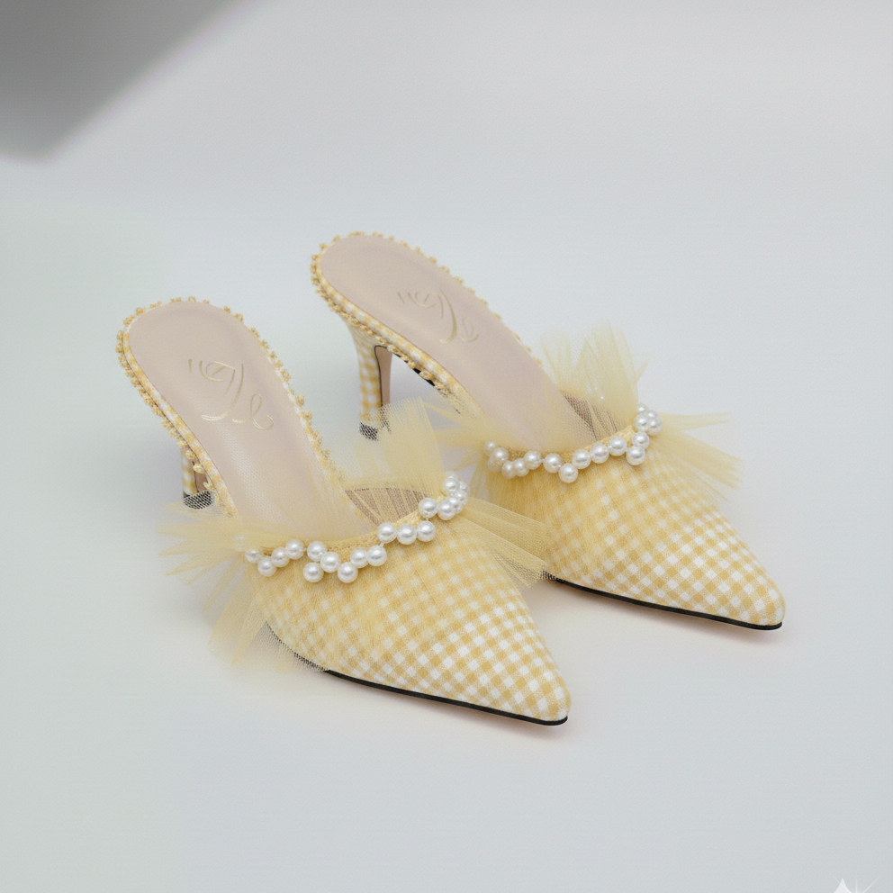 Yellow checkered high-heeled shoes with pearl embellishments on a light gray background