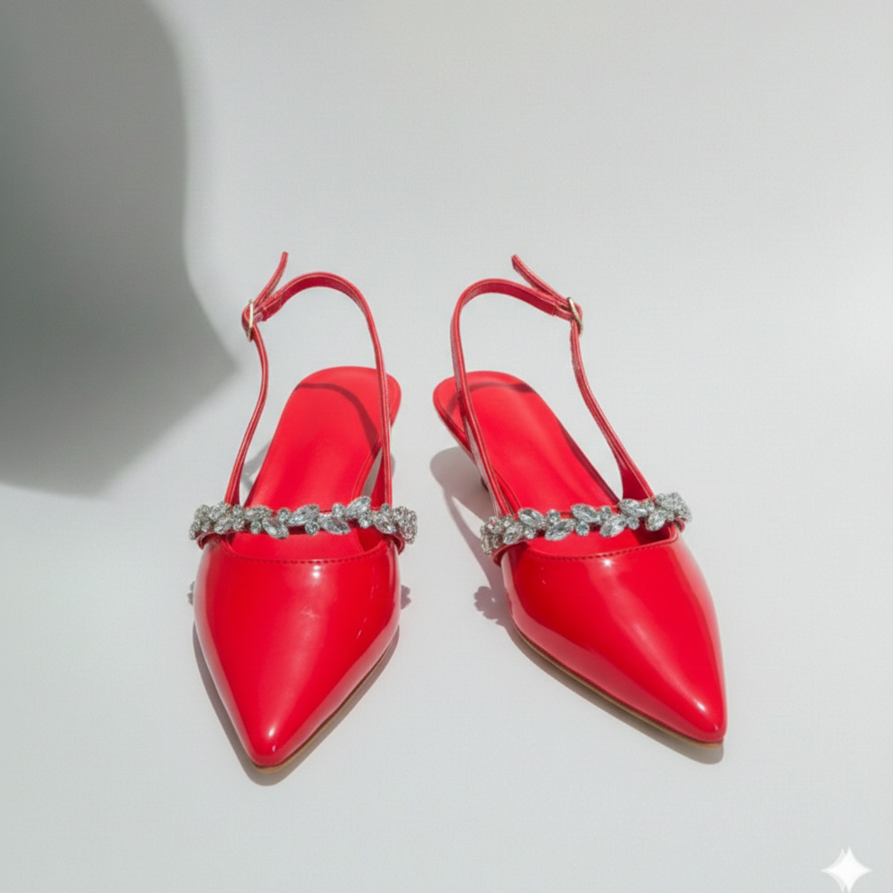 Red pointed-toe shoes with crystal embellishments on a light gray background