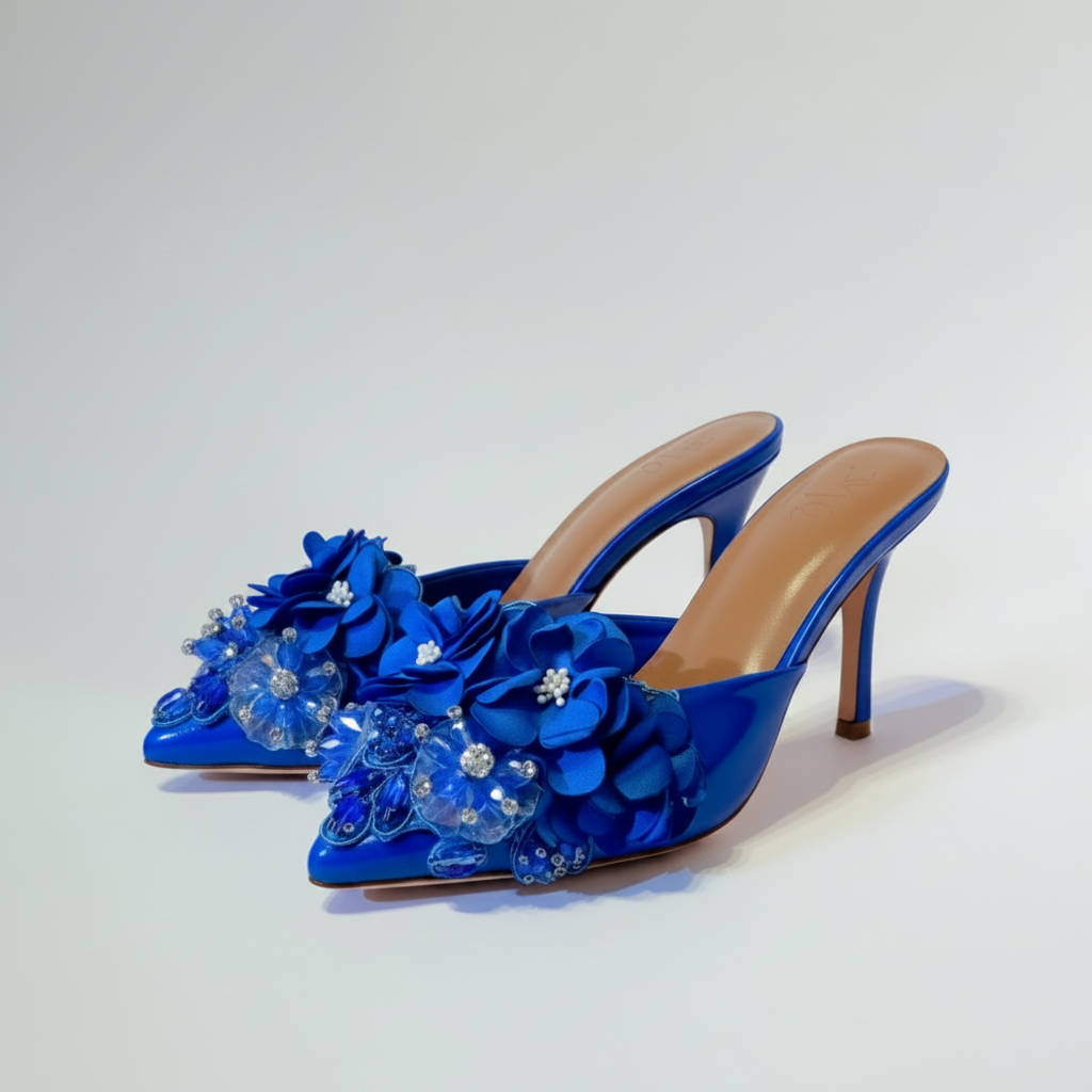 Blue high-heeled shoes with floral decorations on a light gray background