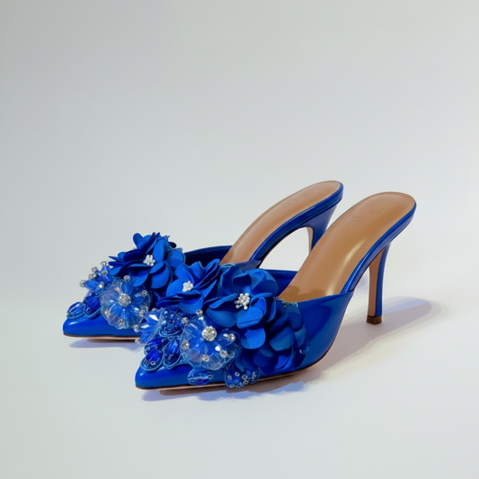 Blue high-heeled shoes with floral decorations on a light gray background