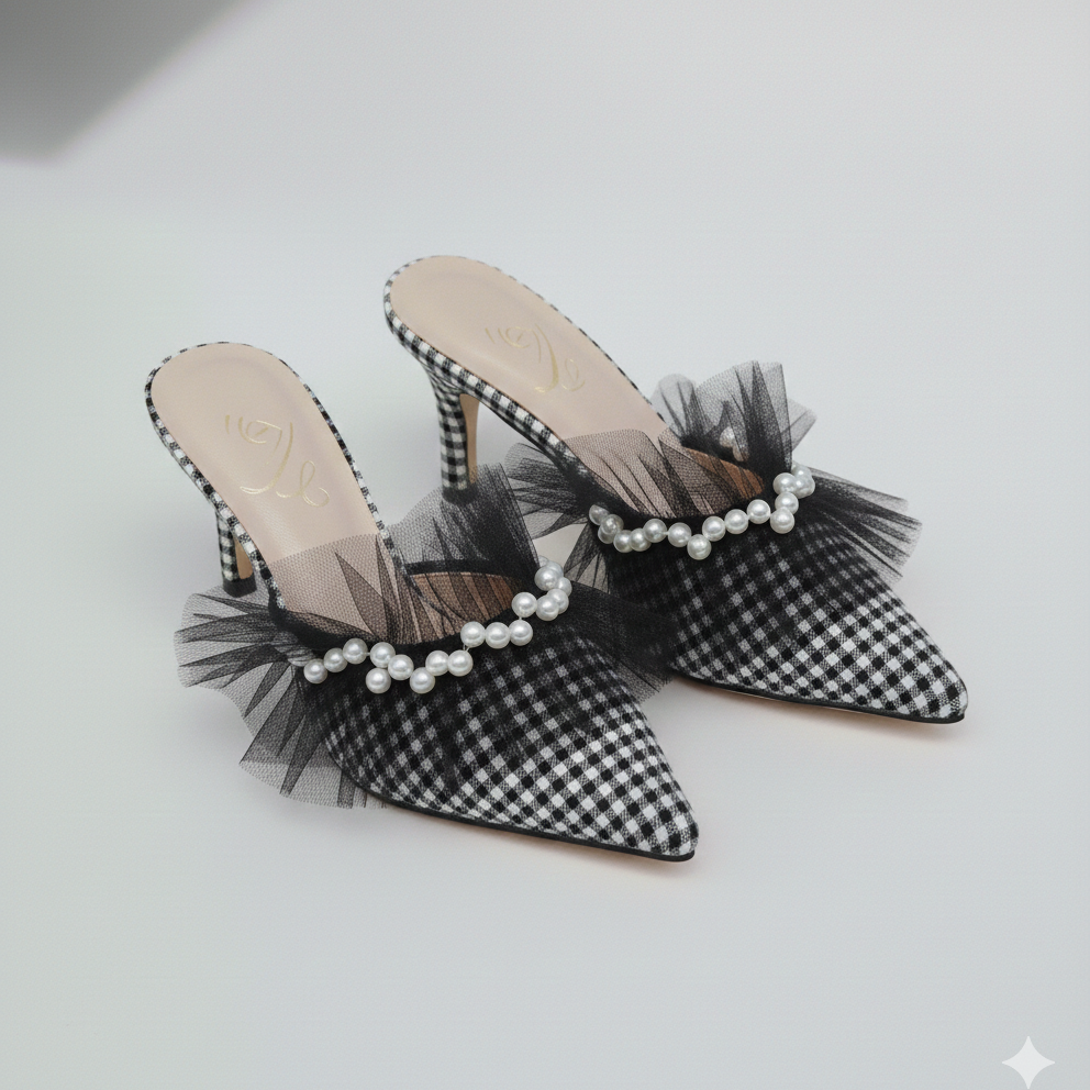 Black and white checkered high-heeled shoes with tulle and pearl details on a light gray background