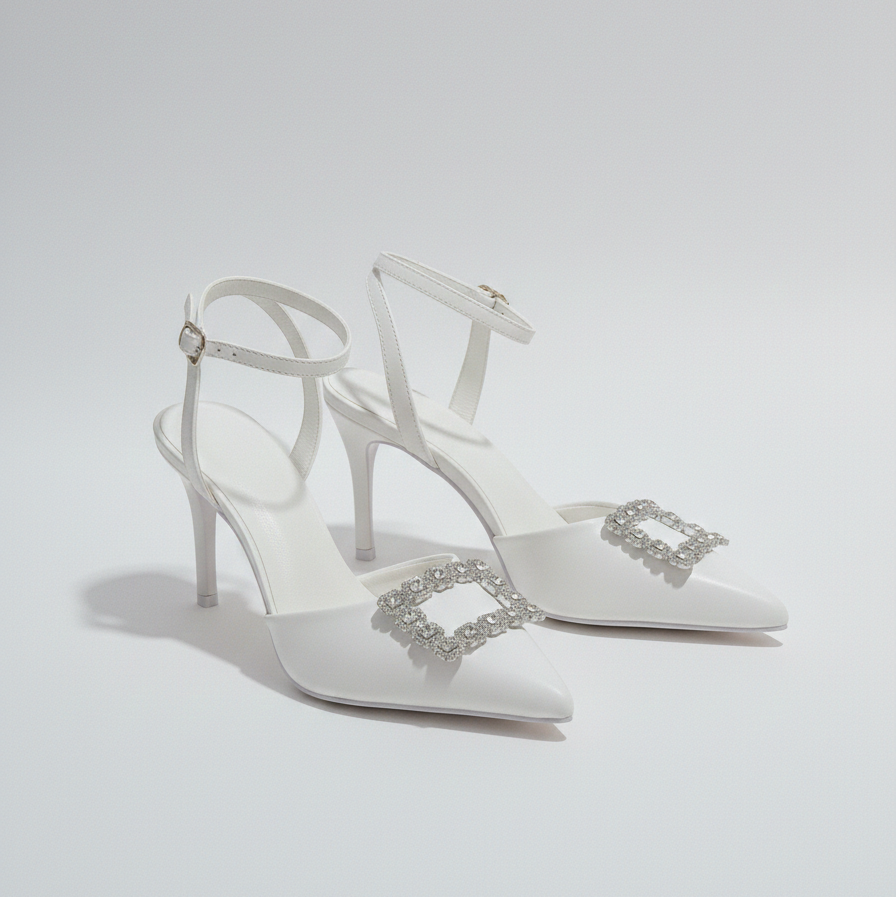 White high-heeled shoes with decorative straps on a light gray background