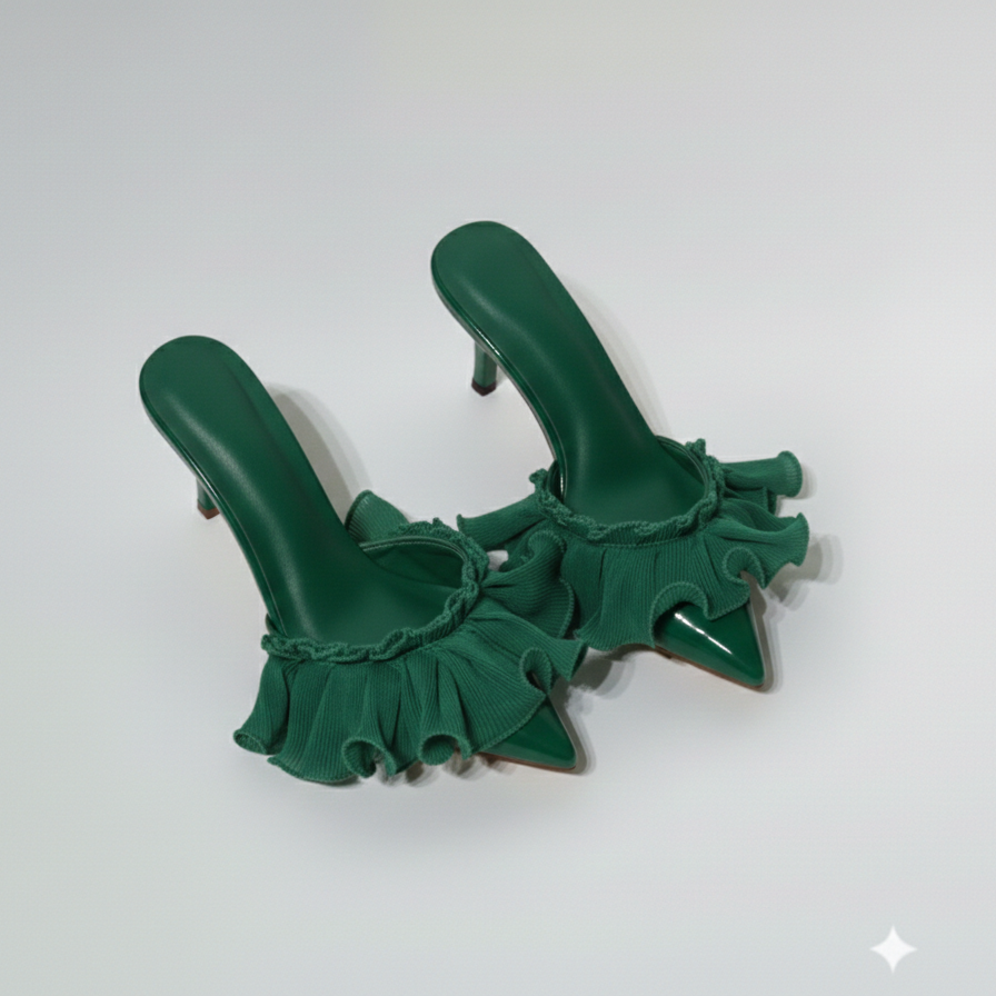 Pair of green high-heeled shoes with ruffled details on a white background