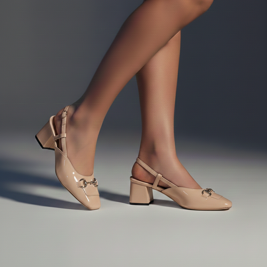 Beige high-heeled shoes worn by a person on a gray background