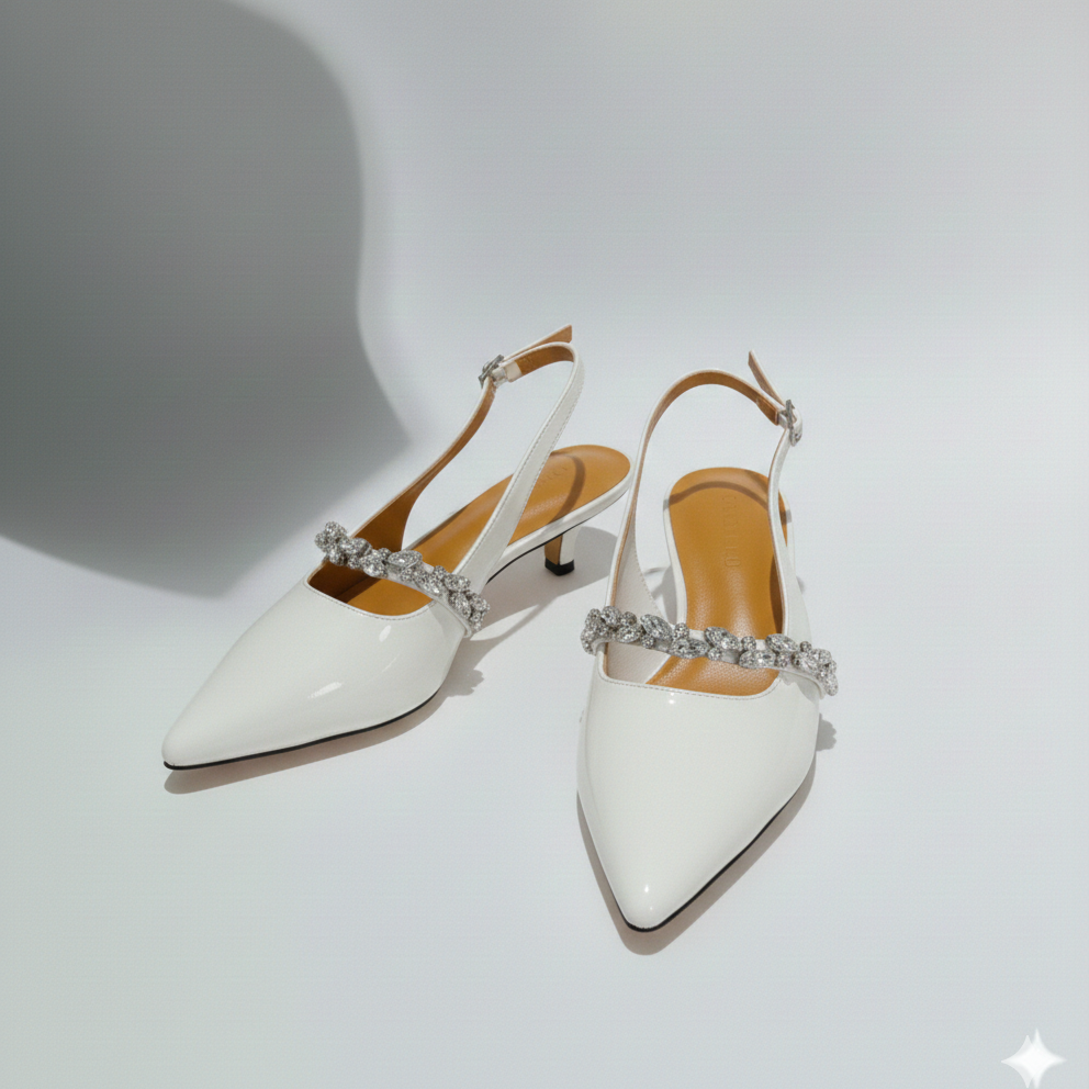 White high-heeled shoes with crystal embellishments on a light gray background